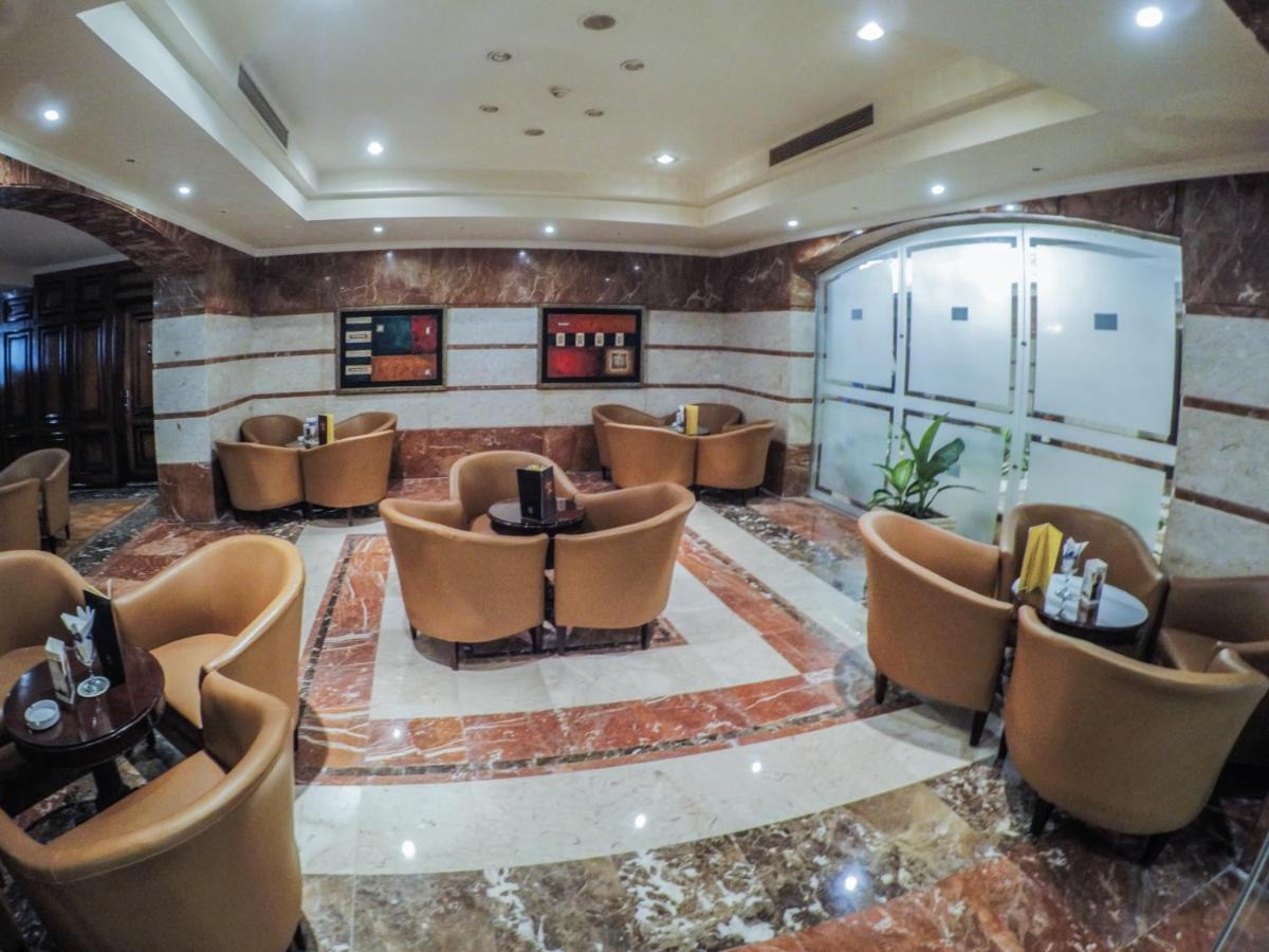 Sunrise Alex Avenue Hotel Αλεξάνδρεια Εξωτερικό φωτογραφία The photo depicts a stylish lounge area with several comfortable seating arrangements. There are plush, curved chairs arranged around small tables, likely intended for coffee or casual gatherings. The floor features a polished marble design, and the 